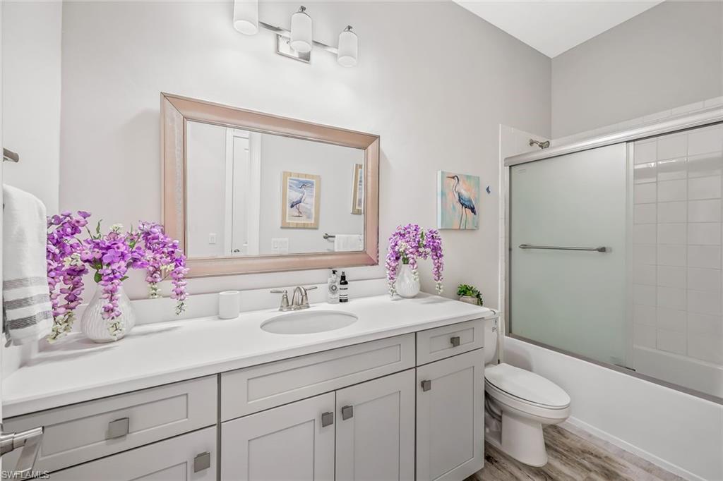 15495 Rio Ponace Court Naples, FL 34114 - Photo 16 of 43 Full bath featuring vanity, shower / bath combination with glass door, and wood finished floors