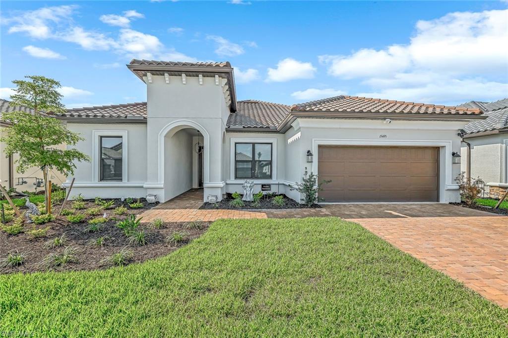 15495 Rio Ponace Court Naples, FL 34114 - Photo 2 of 43 Mediterranean / spanish-style house with a tiled roof, decorative driveway, stucco siding, a garage, and a front yard