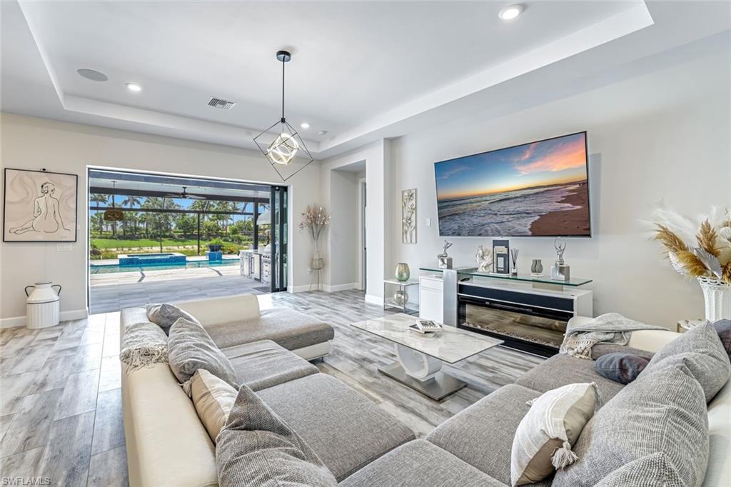 15495 Rio Ponace Court Naples, FL 34114 - Photo 21 of 43 Living area featuring a raised ceiling, light wood-style floors, and recessed lighting
