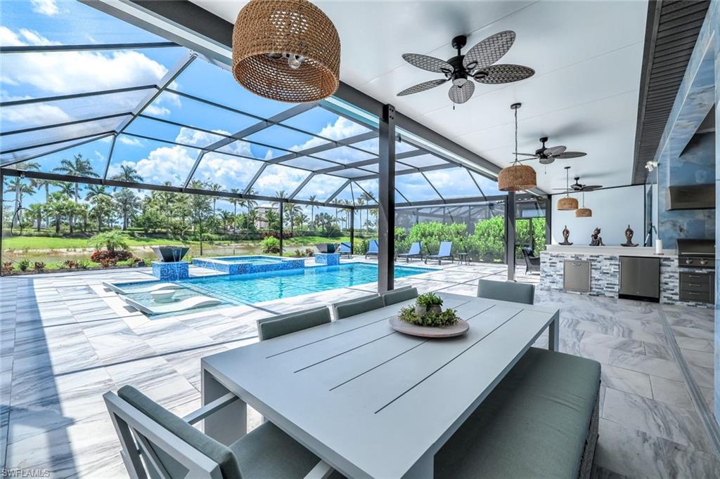 15495 Rio Ponace Court Naples, FL 34114 - Photo 23 of 43 View of patio / terrace with an outdoor kitchen, ceiling fan, a pool with connected hot tub, a lanai, and outdoor dining space