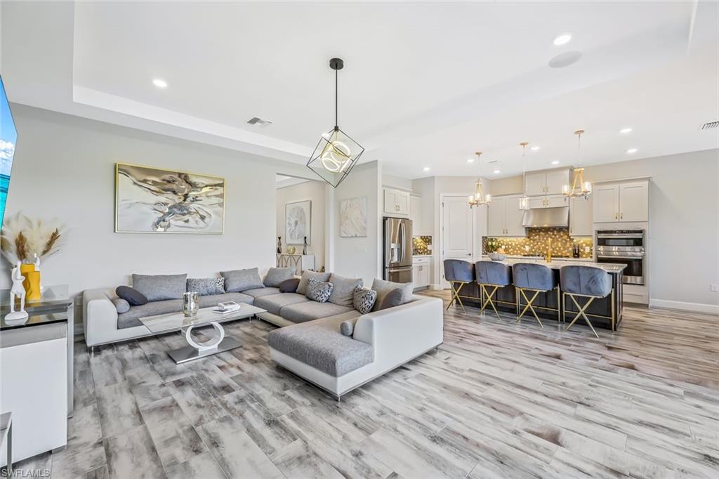 15495 Rio Ponace Court Naples, FL 34114 - Photo 3 of 43 Living room with a chandelier, recessed lighting, and light wood-style floors