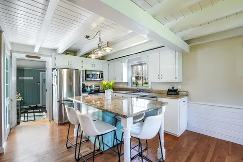 a kitchen with stainless steel appliances kitchen island granite countertop a table chairs in it and wooden floors