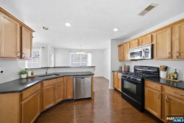 a kitchen with stainless steel appliances granite countertop a stove a sink and a granite counter tops with wooden floors