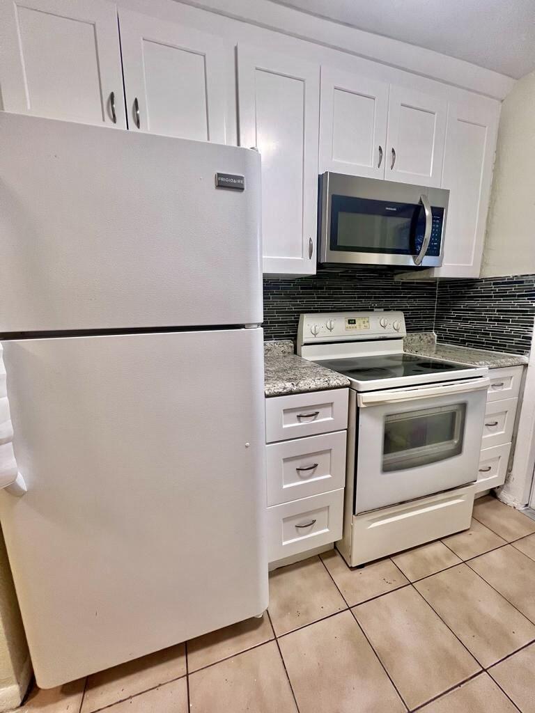 a white refrigerator freezer and a stove sitting inside of a kitchen with granite countertop cabinets