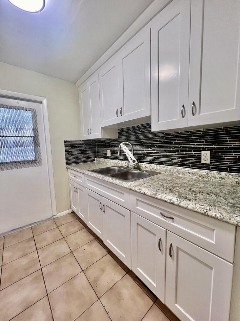 645 Southwest 20th Court, Unit 20 Delray Beach, FL 33445 - Photo 2 of 18 a kitchen with granite countertop white cabinets and sink