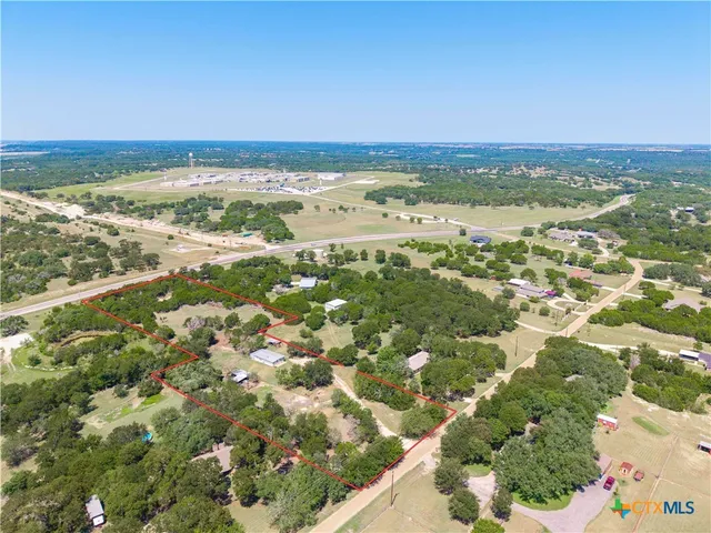 an aerial view of residential houses with outdoor space and trees