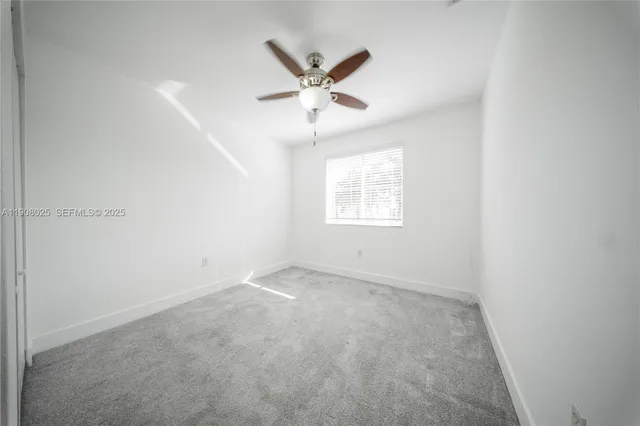 an empty room with a ceiling fan and windows