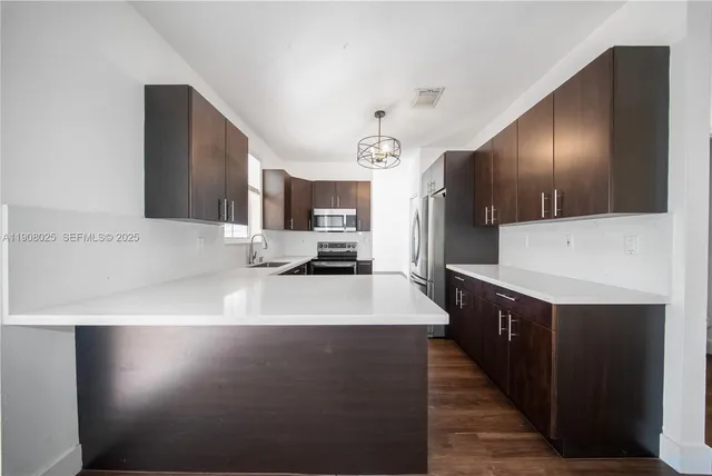 a large kitchen with stainless steel appliances a large counter top a stove and a refrigerator