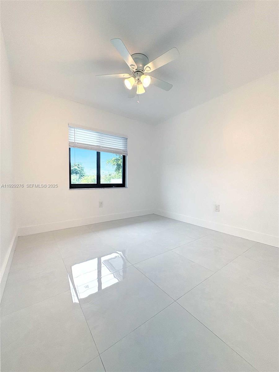 3079 Northwest 11th Street, Unit 3053 Miami, FL 33125 - Photo 2 of 11 an empty room with windows and chandelier fan