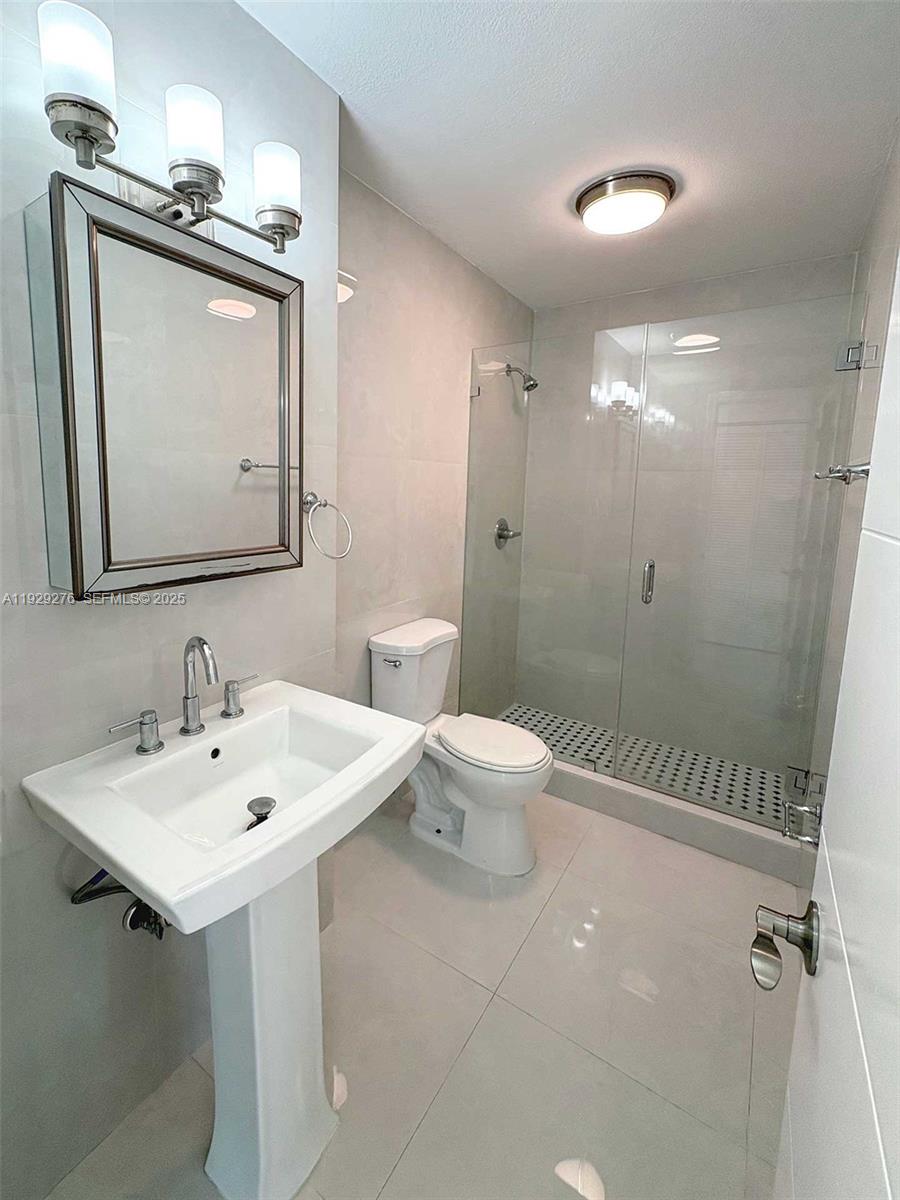3079 Northwest 11th Street, Unit 3053 Miami, FL 33125 - Photo 10 of 11 a bathroom with a toilet a sink a mirror and vanity