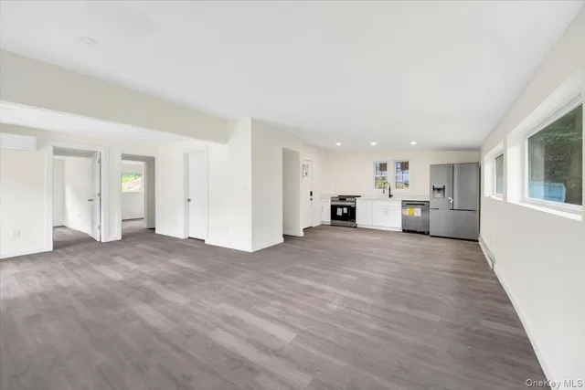 a view of empty room with kitchen and window
