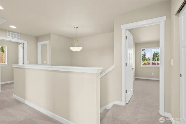 a view of a hallway with wooden floor and a bathroom