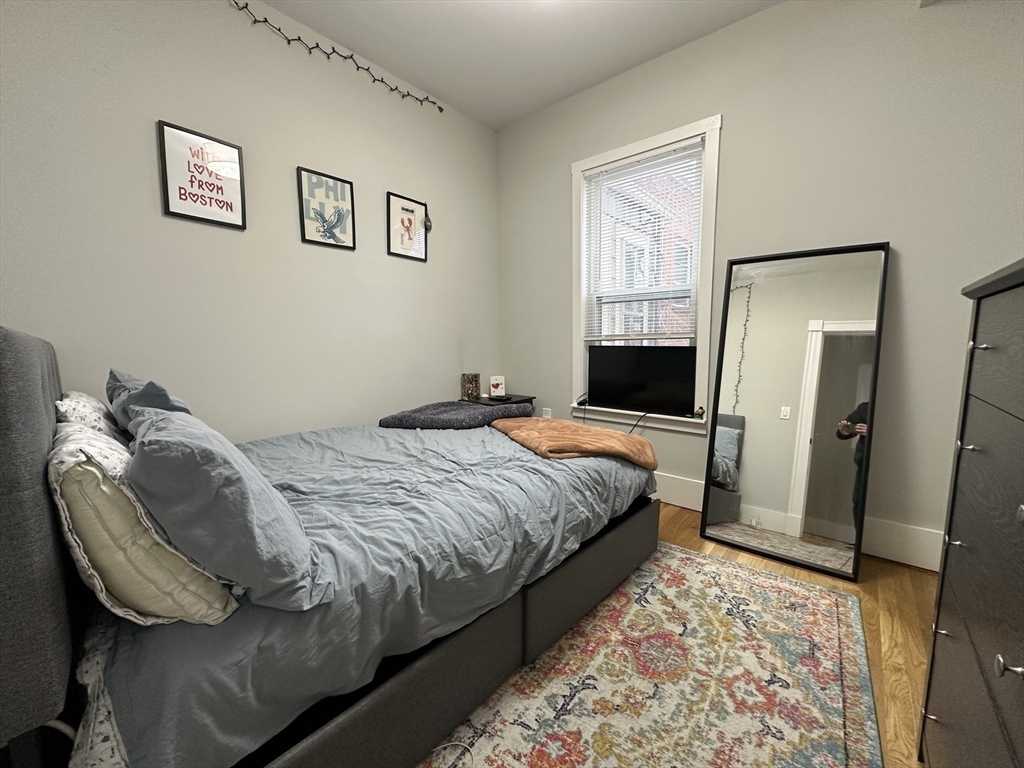 68 L Street, Unit 1 Boston, MA 02127 - Photo 4 of 12 a bedroom with a bed and a mirror