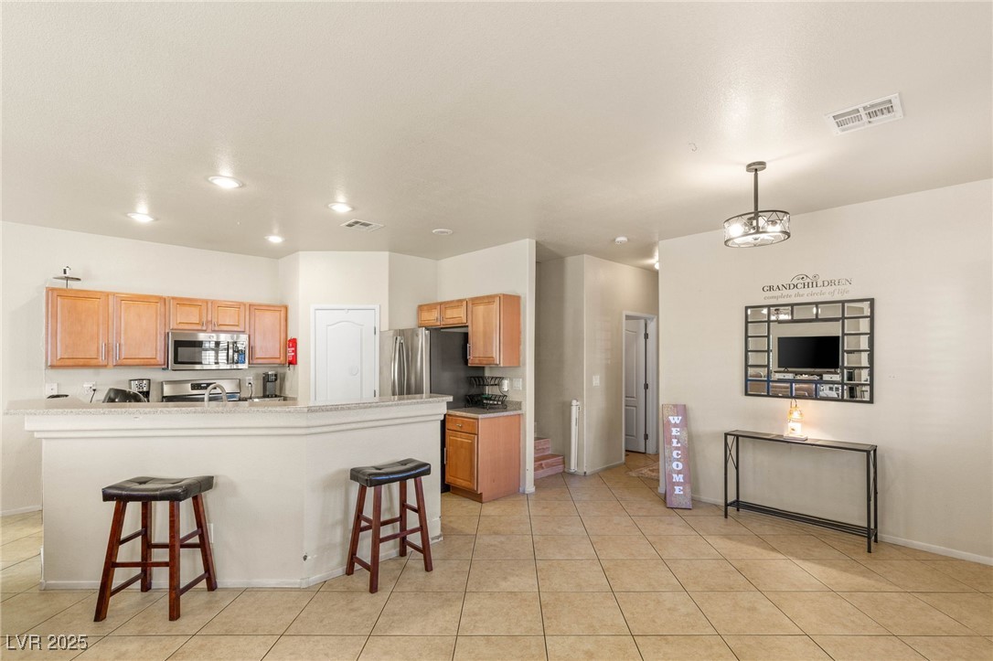 1591 Rusty Ridge Lane Henderson, NV 89002 - Photo 10 of 27 Kitchen with a breakfast bar, light tile patterned floors, appliances with stainless steel finishes, hanging light fixtures, and recessed lighting