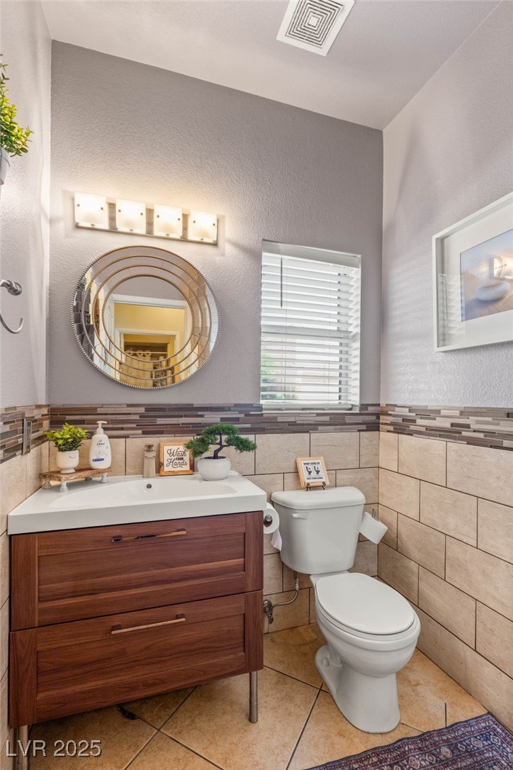 1591 Rusty Ridge Lane Henderson, NV 89002 - Photo 13 of 27 Bathroom with a textured wall, vanity, tile walls, light tile patterned flooring, and a wainscoted wall