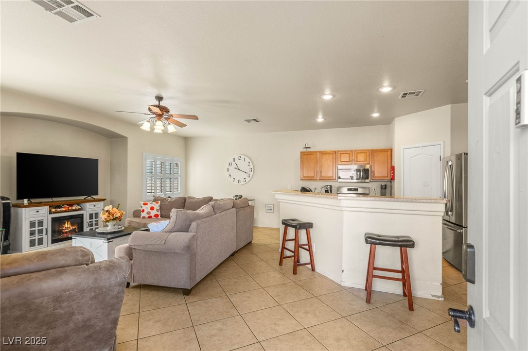 1591 Rusty Ridge Lane Henderson, NV 89002 - Photo 5 of 27 Living room with light tile patterned floors, a warm lit fireplace, recessed lighting, and a ceiling fan