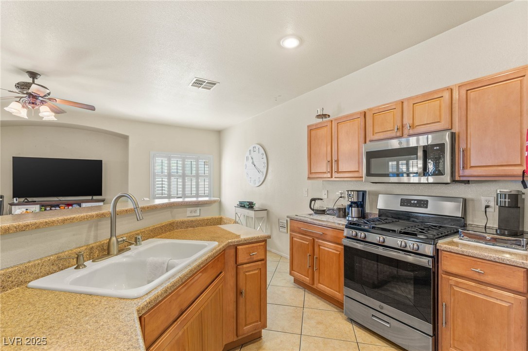 1591 Rusty Ridge Lane Henderson, NV 89002 - Photo 27 of 27 Kitchen featuring stainless steel appliances, light tile patterned floors, open floor plan, and ceiling fan