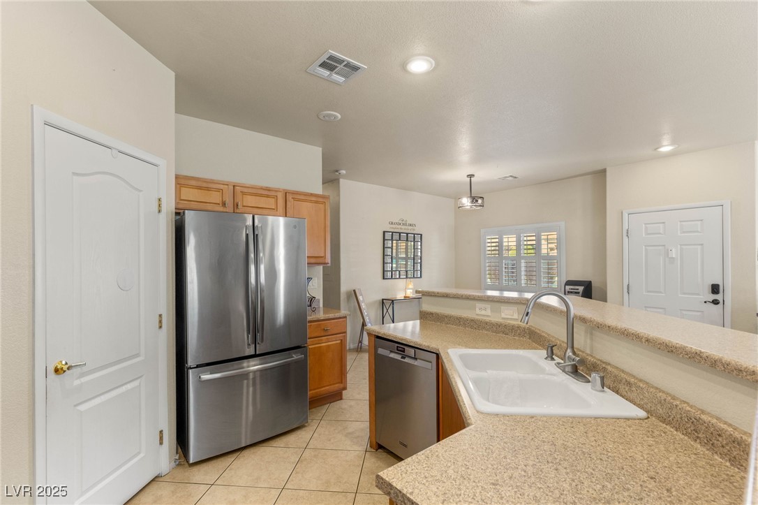 1591 Rusty Ridge Lane Henderson, NV 89002 - Photo 8 of 27 Kitchen featuring appliances with stainless steel finishes, light countertops, light tile patterned flooring, and hanging light fixtures
