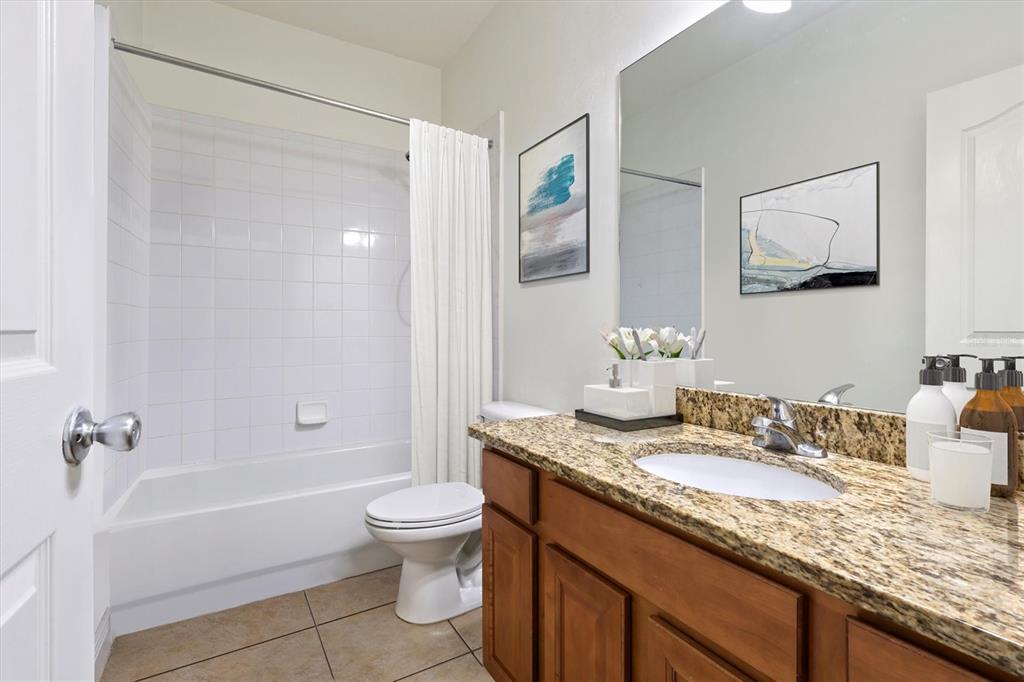 7909 Southwest 87th Terrace Gainesville, FL 32608 - Photo 15 of 17 a bathroom with a granite countertop sink a toilet and shower