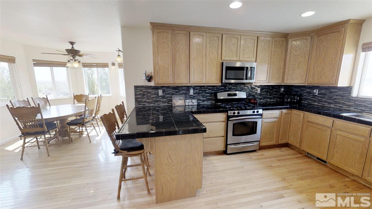 6080 Range Reno, NV 89510 - Photo 5 of 33 a kitchen with stainless steel appliances a stove a sink a microwave a dining table and chairs