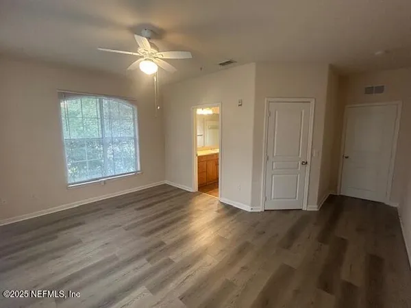 an empty room with wooden floor fan and windows