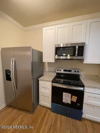 a view of a kitchen with kitchen island a sink wooden floor and a chandelier