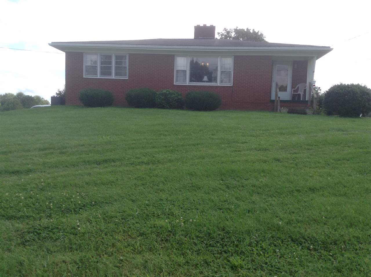 a view of a yard in front of a brick house with large windows