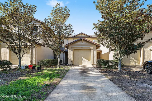 a front view of a house with a garden and trees