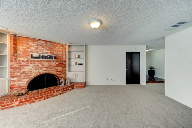 a view of an empty room with fireplace and a window