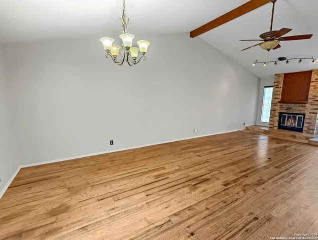 a view of an empty room with a chandelier fan and wooden floor