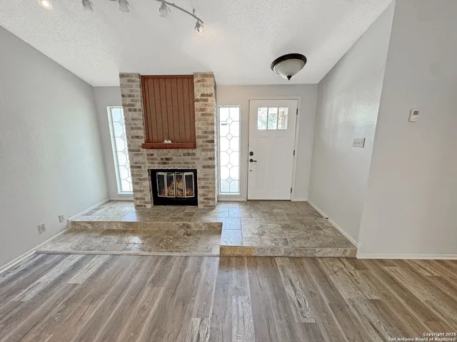 a view of empty room with wooden floor and fireplace