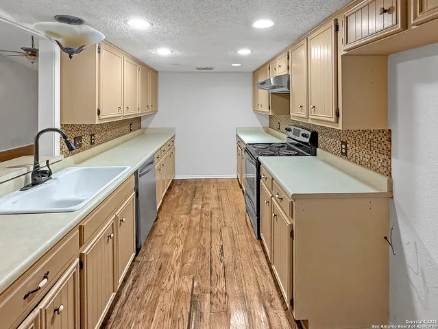 a kitchen with kitchen island granite countertop a sink stove and cabinets