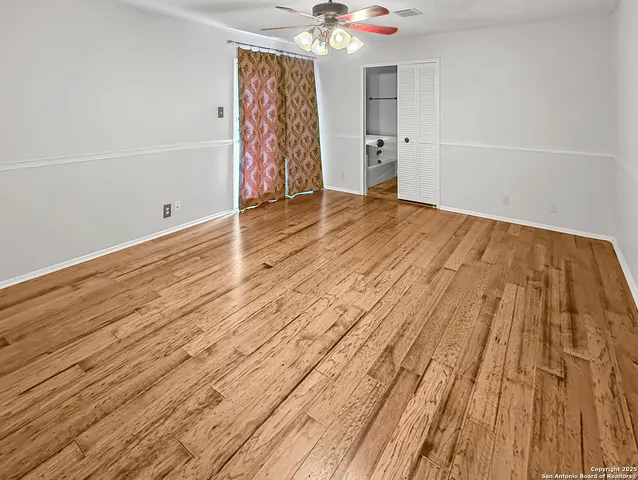 a view of a room with wooden floor and a ceiling fan