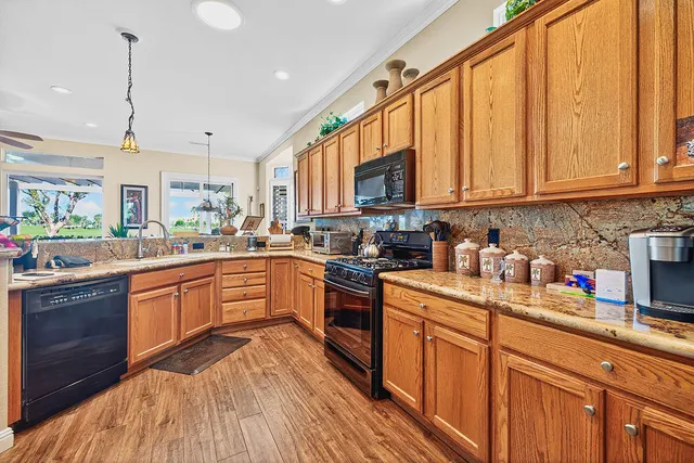 a kitchen with stainless steel appliances granite countertop a stove a sink dishwasher and a refrigerator with wooden floor