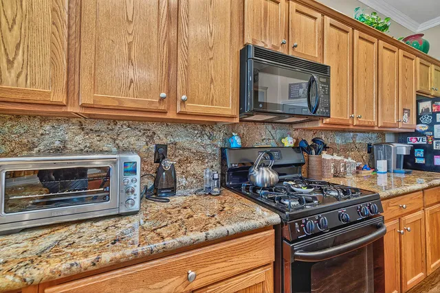 a kitchen with granite countertop a stove top oven microwave and cabinets