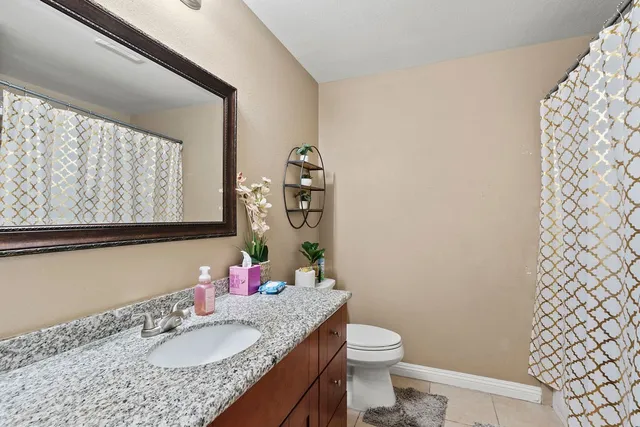 a bathroom with a granite countertop sink toilet and mirror