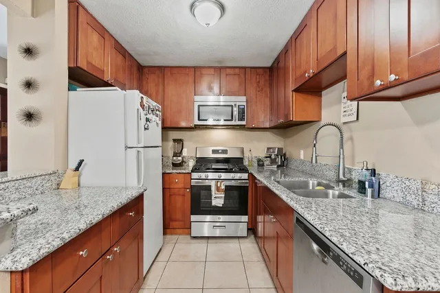 a kitchen with granite countertop a sink stove and refrigerator