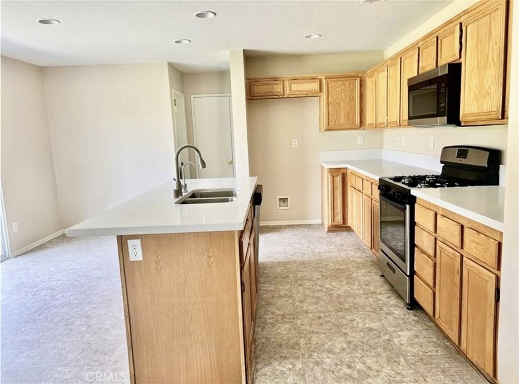 32040 Poppy Way Lake Elsinore, CA 92532 - Photo 6 of 27 a kitchen with stainless steel appliances a sink stove refrigerator and cabinets