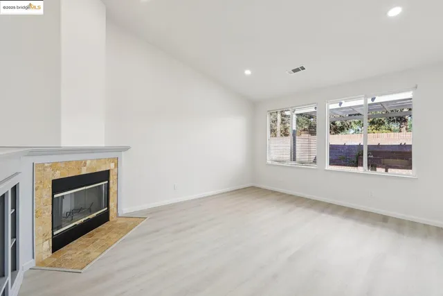 an empty room with windows and fireplace