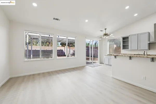 a view of an empty room with kitchen and a window