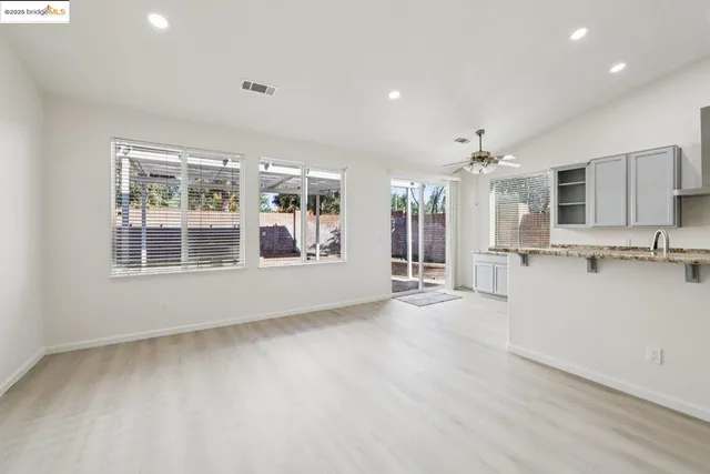 a view of an empty room with kitchen and a window
