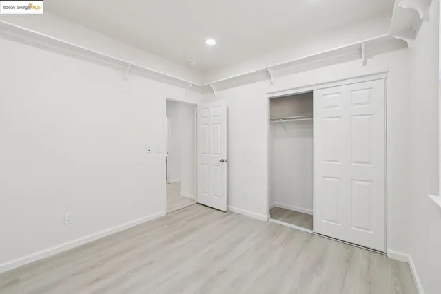 an empty room with wooden floor & closet and windows