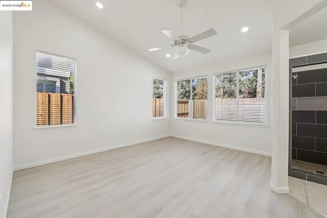 a view of an empty room with a window and wooden floor