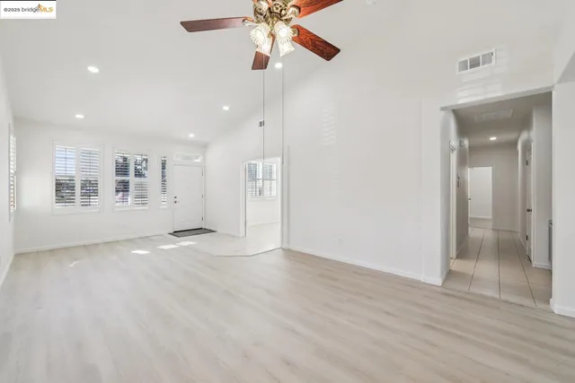 a view of an empty room with window and wooden floor
