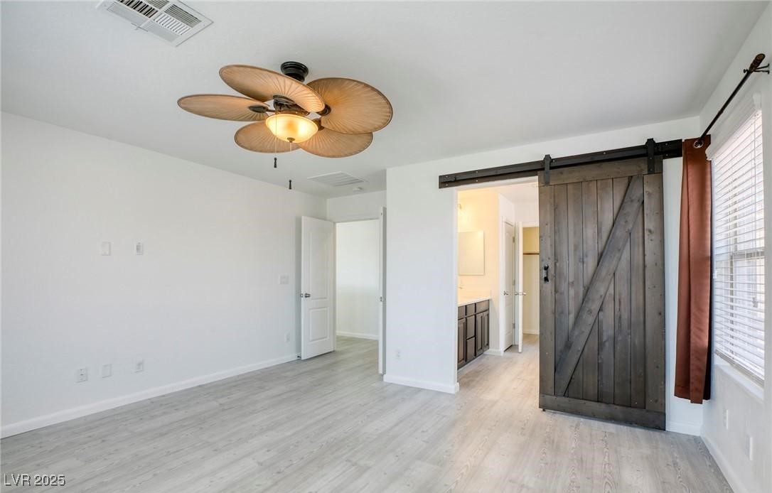 7600 Finishing Touch Court Las Vegas, NV 89149 - Photo 15 of 32 Empty room featuring light wood finished floors, a barn door, and ceiling fan
