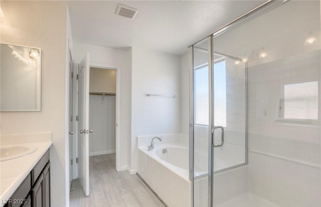 7600 Finishing Touch Court Las Vegas, NV 89149 - Photo 18 of 32 Bathroom with vanity, a stall shower, a bath, a walk in closet, and light wood finished floors