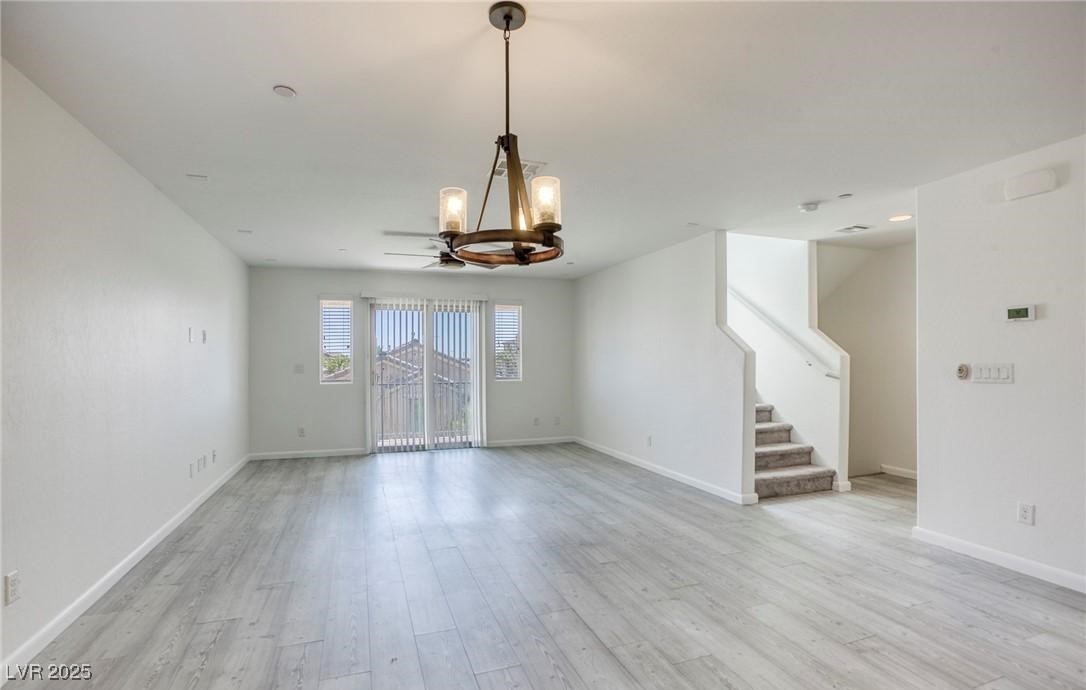 7600 Finishing Touch Court Las Vegas, NV 89149 - Photo 4 of 32 Unfurnished room featuring stairway, light wood-style flooring, and a chandelier
