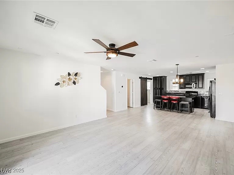 7600 Finishing Touch Court Las Vegas, NV 89149 - Photo 10 of 32 Living area with light wood finished floors, ceiling fan, a barn door, a chandelier, and recessed lighting