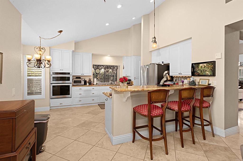 2046 Balboa Circle Vista, CA 92081 - Photo 18 of 37 a room with stainless steel appliances kitchen island granite countertop a dining table chairs and a refrigerator
