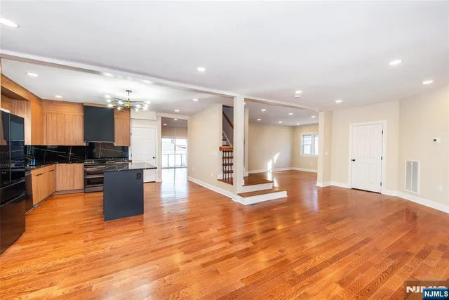 a large kitchen with stainless steel appliances a large counter top a stove and a refrigerator